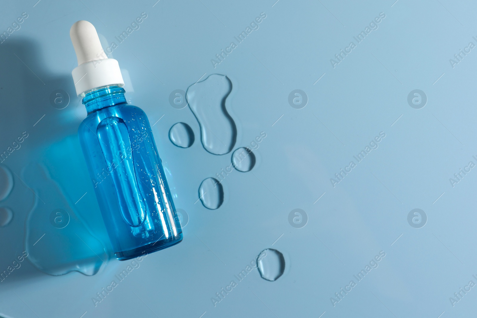 Photo of Bottle of cosmetic serum on light blue background, top view. Space for text