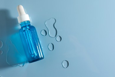 Bottle of cosmetic serum on light blue background, top view. Space for text