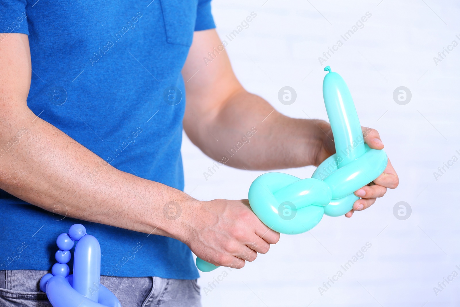 Photo of Man making balloon figure on blurred background, closeup