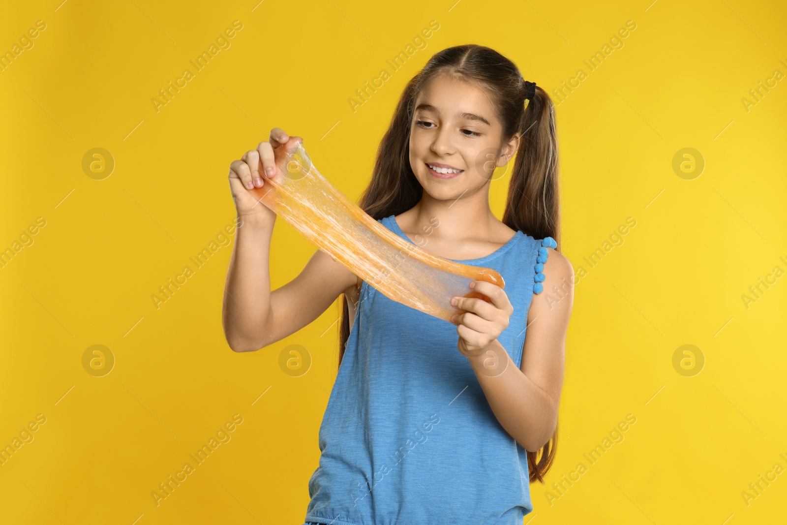 Photo of Preteen girl with slime on yellow background