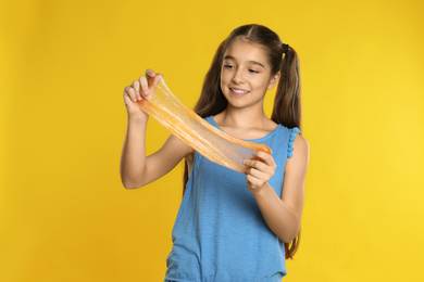 Preteen girl with slime on yellow background