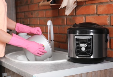 Woman washing modern multi cooker in kitchen sink, closeup