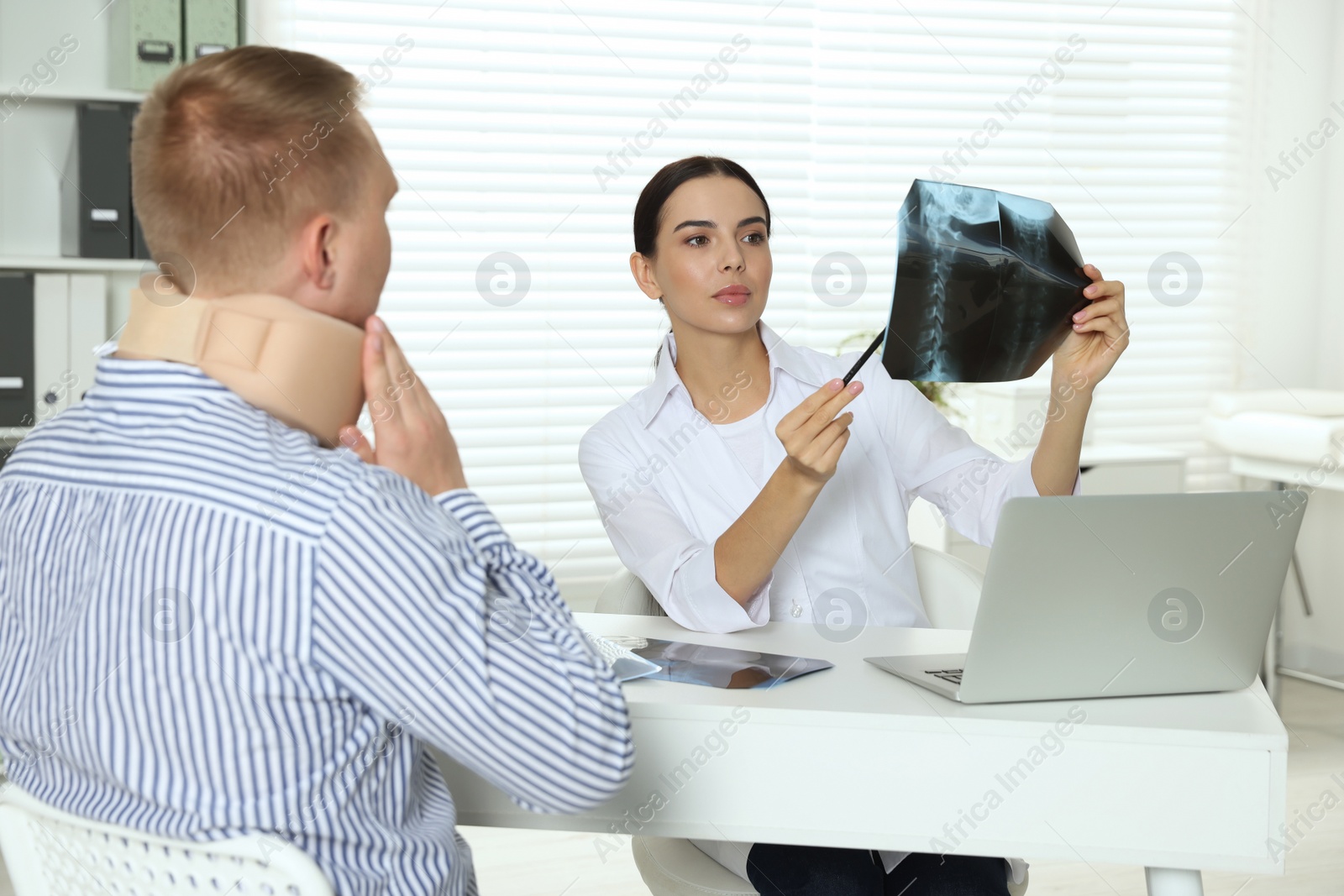 Photo of Doctor with neck MRI image consulting patient in clinic