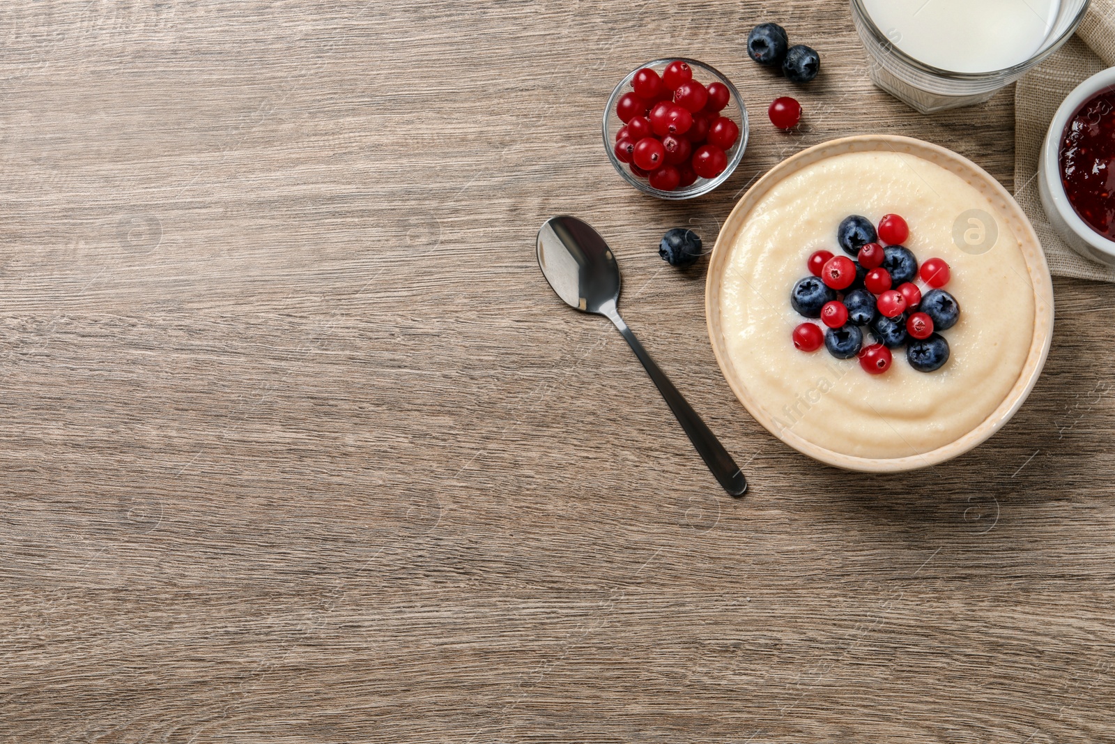 Photo of Delicious semolina pudding with berries on wooden table, flat lay. Space for text