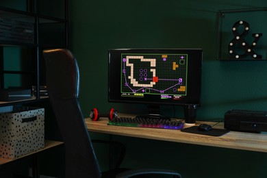 Modern computer and RGB keyboard on wooden table in dark room