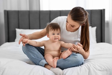 Photo of Mother sitting with her baby on bed at home