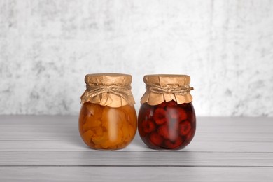 Photo of Jars with canned fruit jams on wooden table