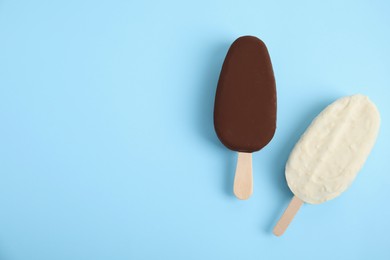 Photo of Glazed ice cream bars on light blue background, flat lay. Space for text