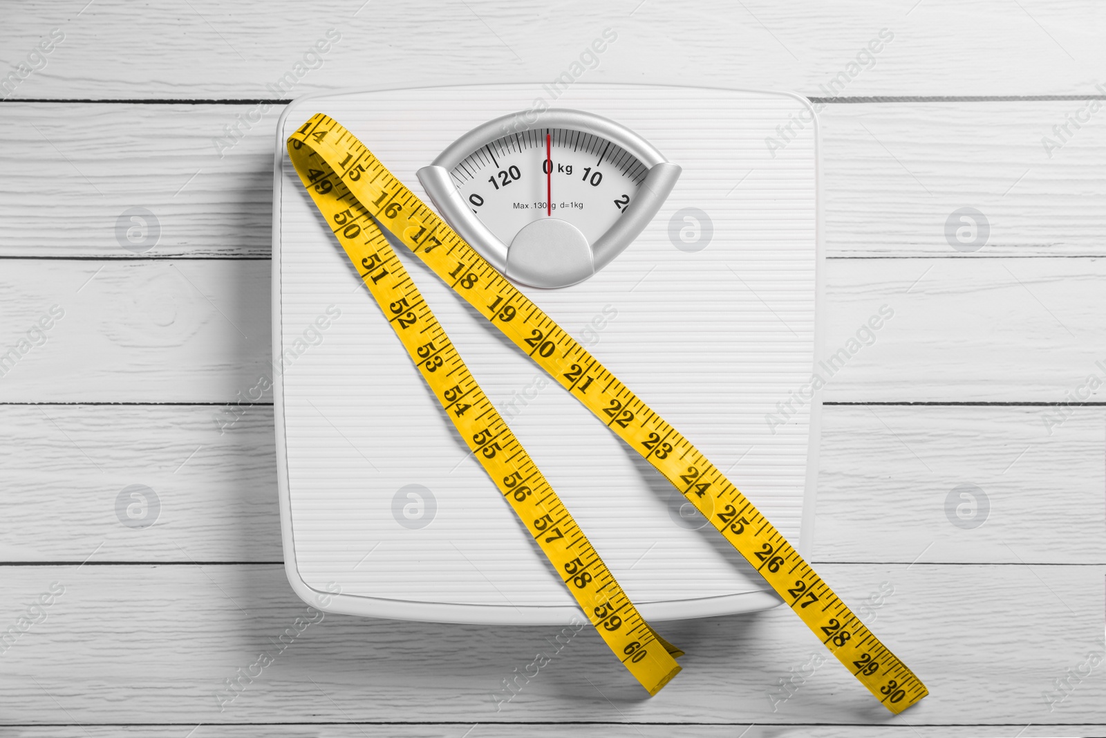 Photo of Scales with measuring tape on white wooden background, top view. Weight loss concept