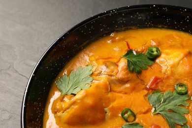 Photo of Tasty chicken curry with parsley and pepper on black textured table, closeup. Space for text