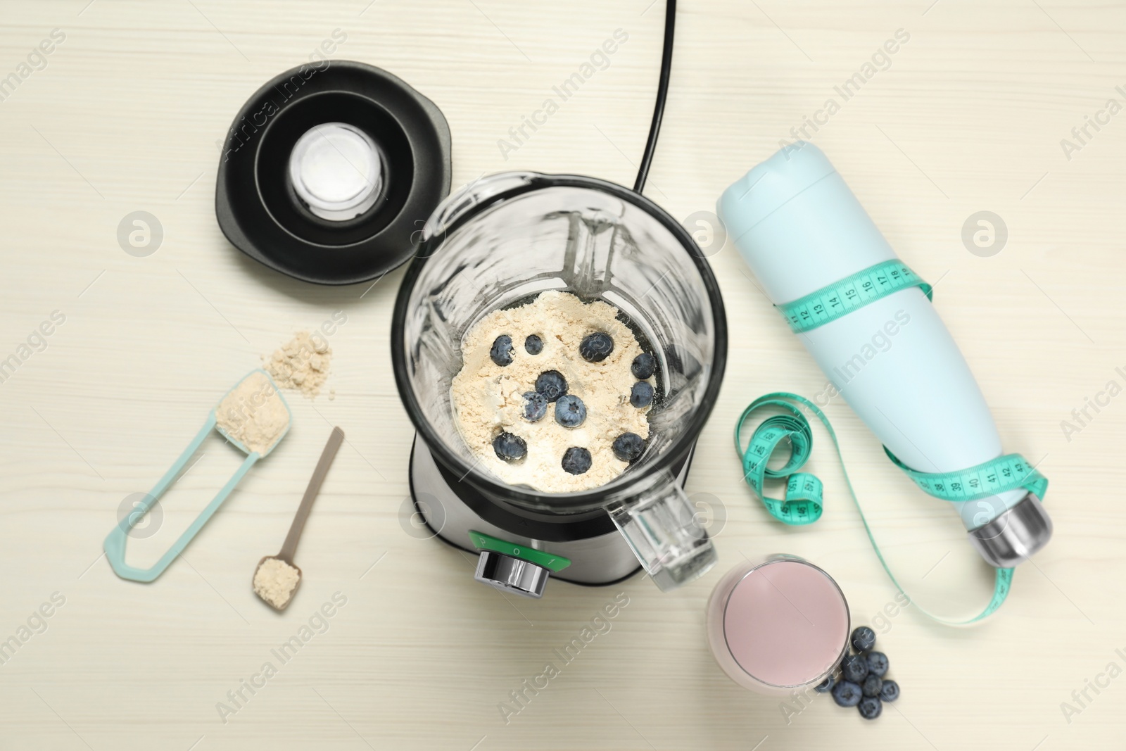 Photo of Making shake. Blueberries and powder in blender on wooden table, flat lay