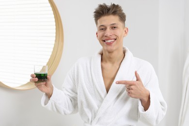 Young man pointing at mouthwash in bathroom