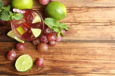 Photo of Refreshing drink with soda water, grapes, lime and mint on wooden table, flat lay. Space for text