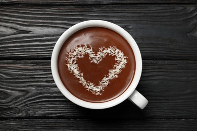Cup of hot chocolate with heart shaped decoration on black wooden table, top view