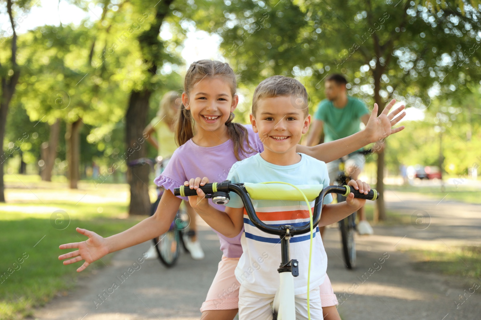 Photo of Happy siblings and their parents riding bicycles in park