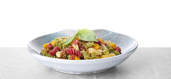 Colorful pasta with basil and cheese on light grey marble table against white background