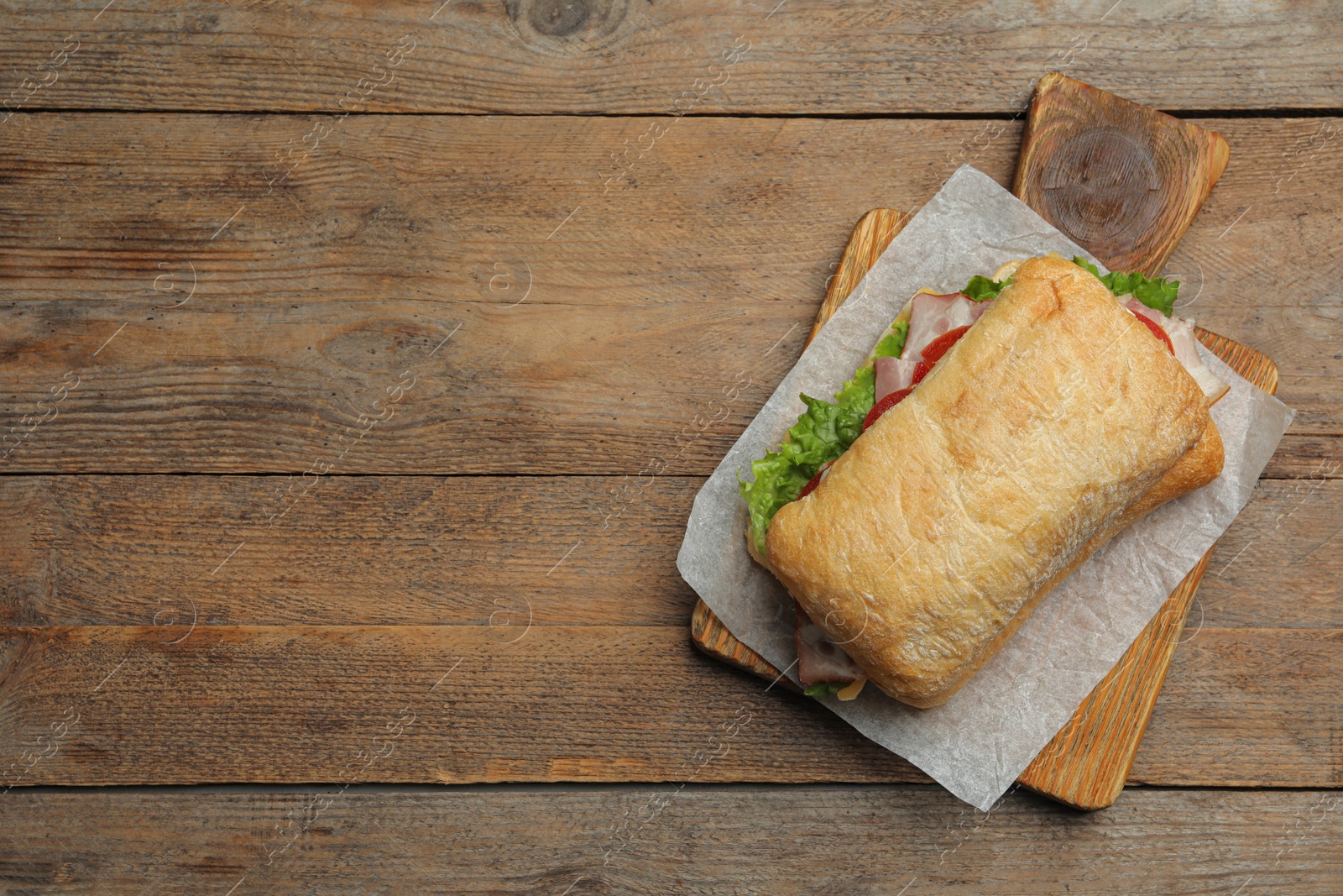 Photo of Delicious sandwich with fresh vegetables on wooden table, top view. Space for text