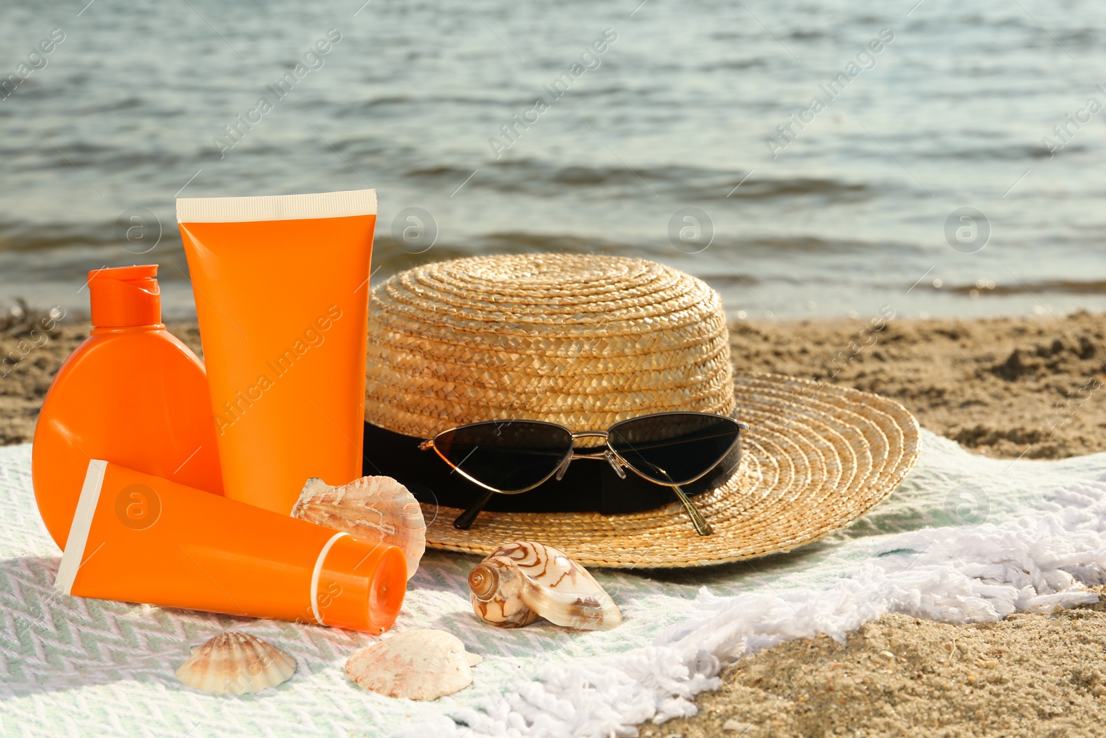 Photo of Sun protection products and beach accessories on blanket near sea