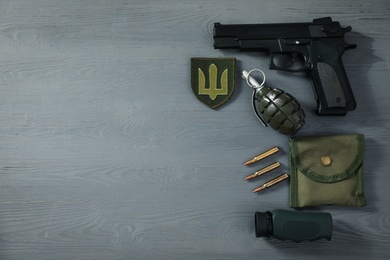 Photo of MYKOLAIV, UKRAINE - SEPTEMBER 26, 2020: Tactical gear and Ukrainian army patch on grey wooden table, flat lay. Space for text