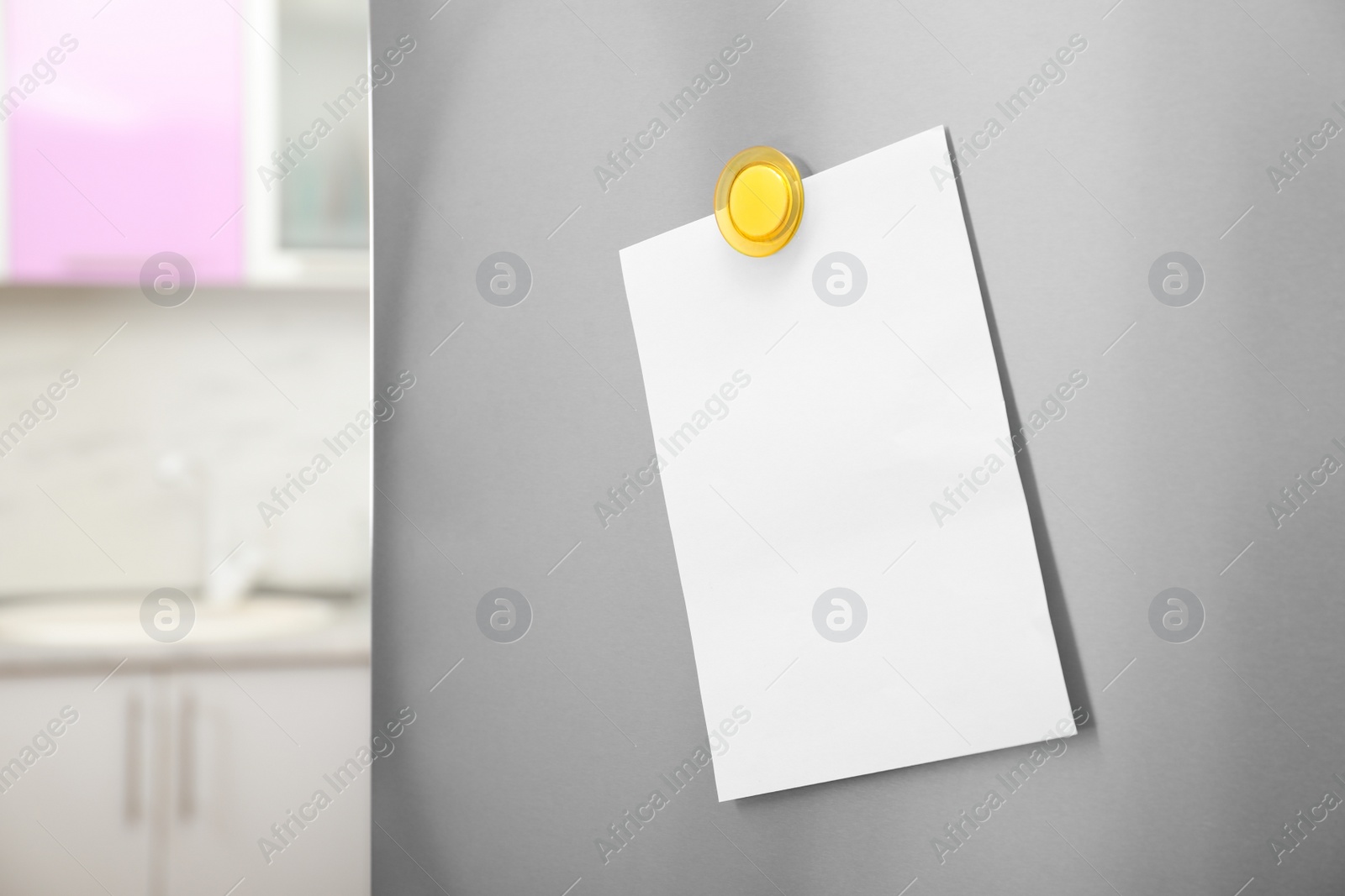 Photo of Empty sheet of paper with magnet on refrigerator door in kitchen. Space for text