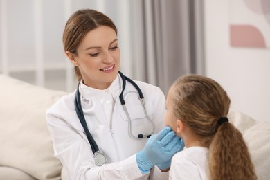 Photo of Smiling doctor examining girl`s oral cavity indoors