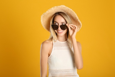 Beautiful woman in stylish sunglasses on yellow background