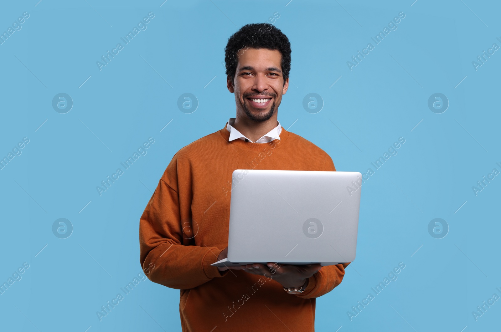 Photo of Happy man with laptop on light blue background