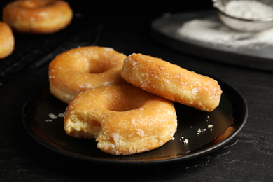 Photo of Sweet delicious glazed donuts on black table