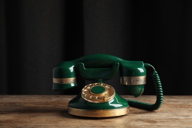 Photo of Vintage corded phone on wooden table against black background