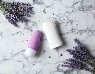 Female deodorant and lavender flowers on white marble background, flat lay