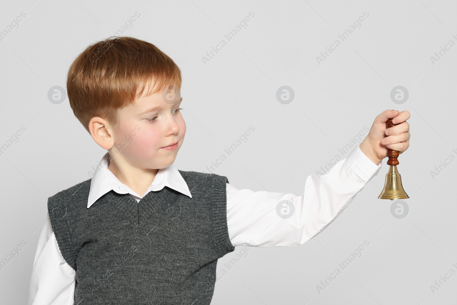 Photo of Pupil with school bell on light grey background