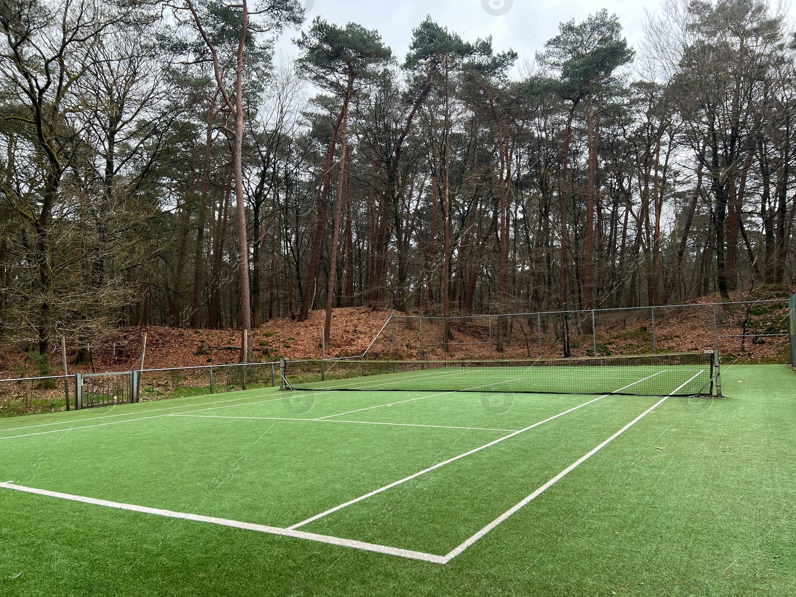 Photo of Tennis court with artificial grass and net outdoors