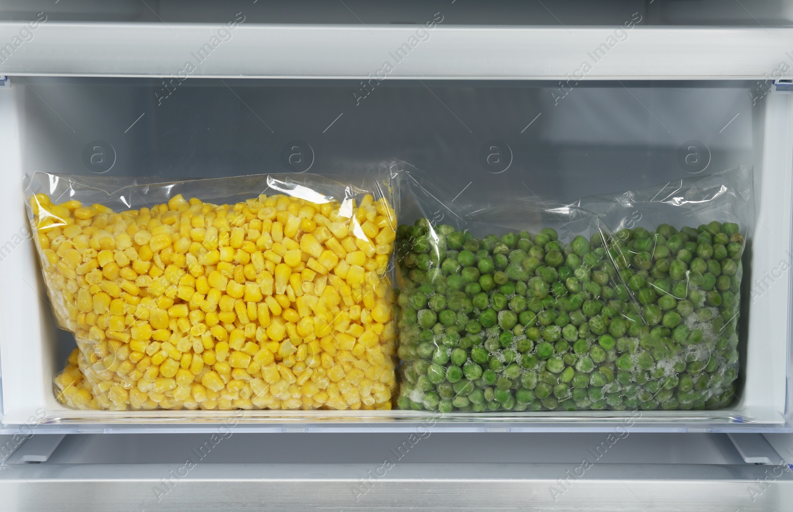 Photo of Bags with frozen vegetables in modern refrigerator