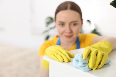 Woman cleaning table with rag at home, selective focus. Space for text