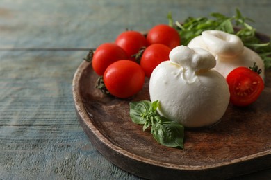 Photo of Delicious burrata cheese with tomatoes on grey wooden table, closeup. Space for text