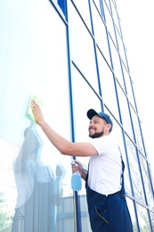 Male worker washing window glass from outside