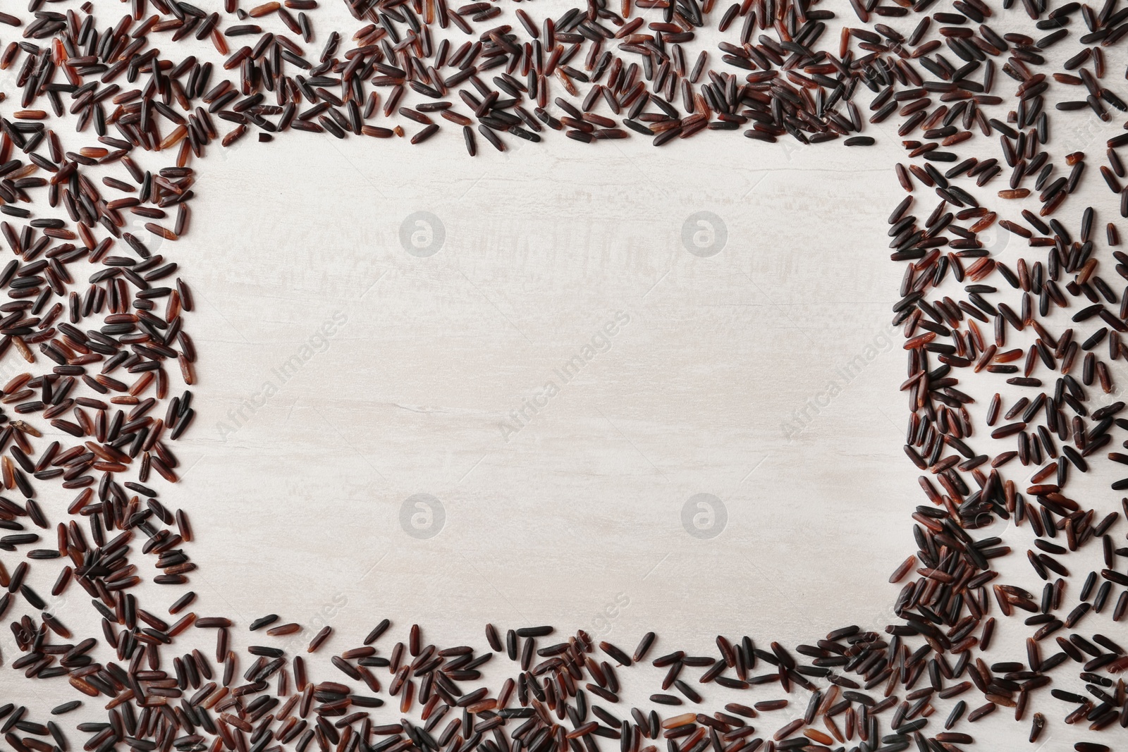 Photo of Frame made with black rice on white wooden background, top view. Space for text