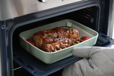 Photo of Chef taking delicious roasted ribs out of oven, closeup