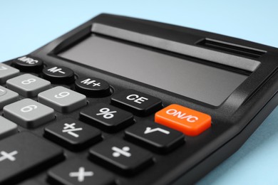 Calculator on light blue background, closeup. Office stationery