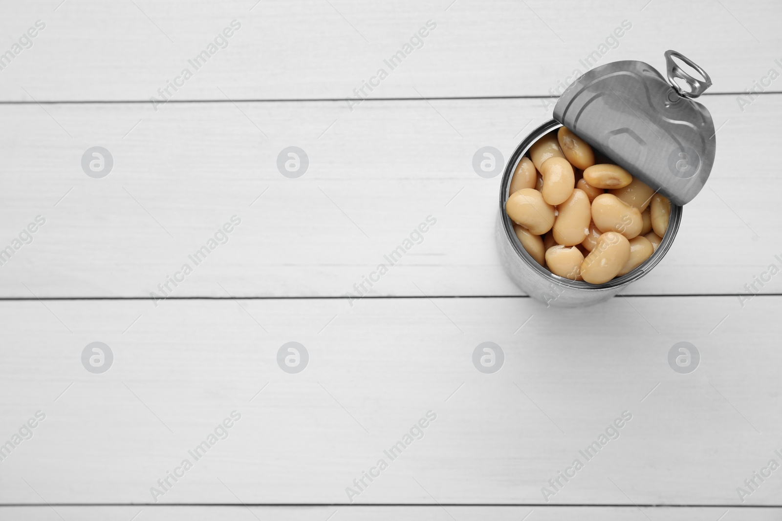 Photo of Tin can of canned kidney beans on white wooden table, top view. Space for text