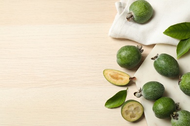 Photo of Flat lay composition with fresh green feijoa fruits on wooden table, space for text