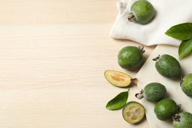 Flat lay composition with fresh green feijoa fruits on wooden table, space for text