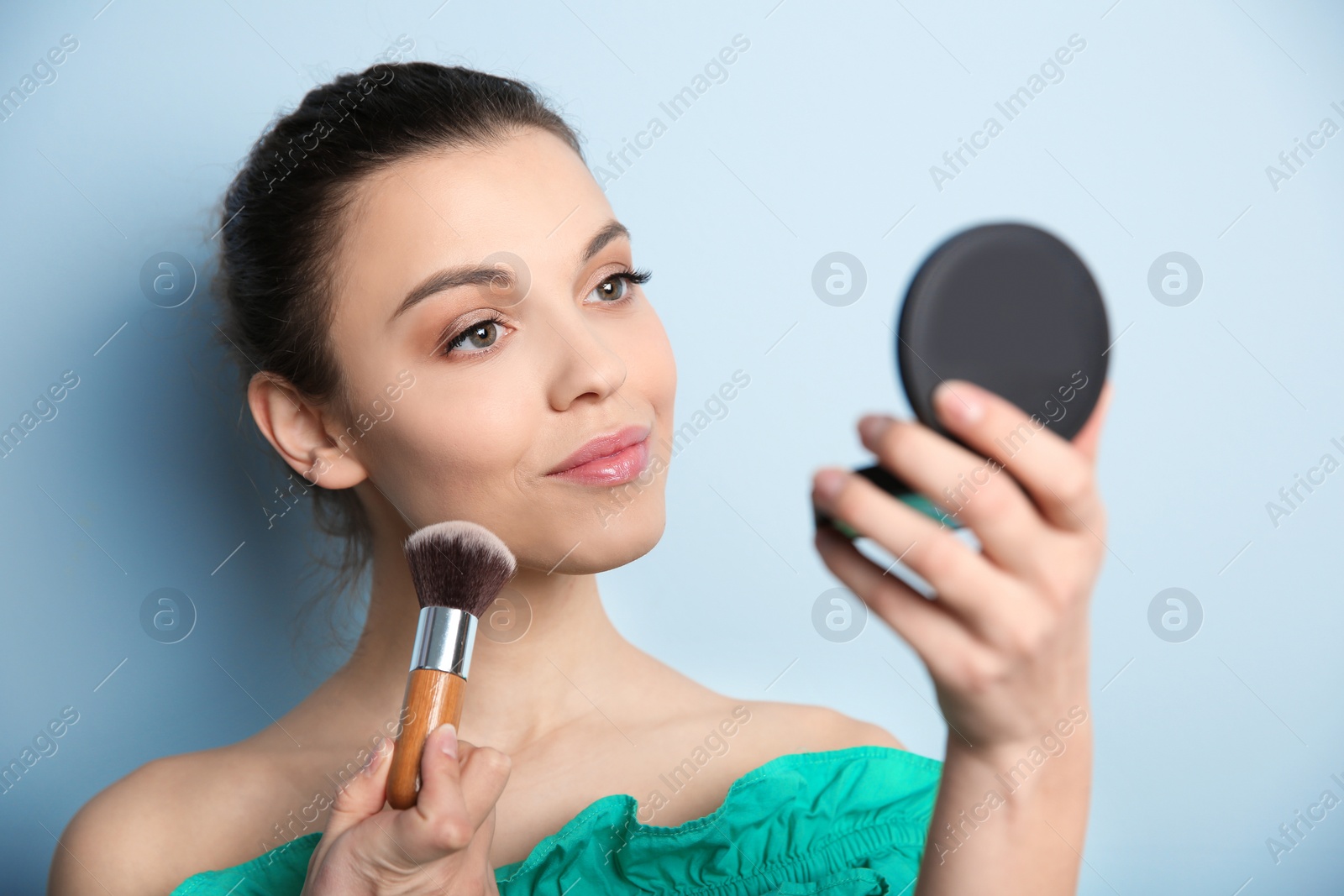 Photo of Young woman applying makeup on color background. Professional cosmetic products