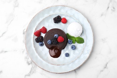 Photo of Delicious chocolate fondant served with fresh berries and ice cream on white marble table, top view