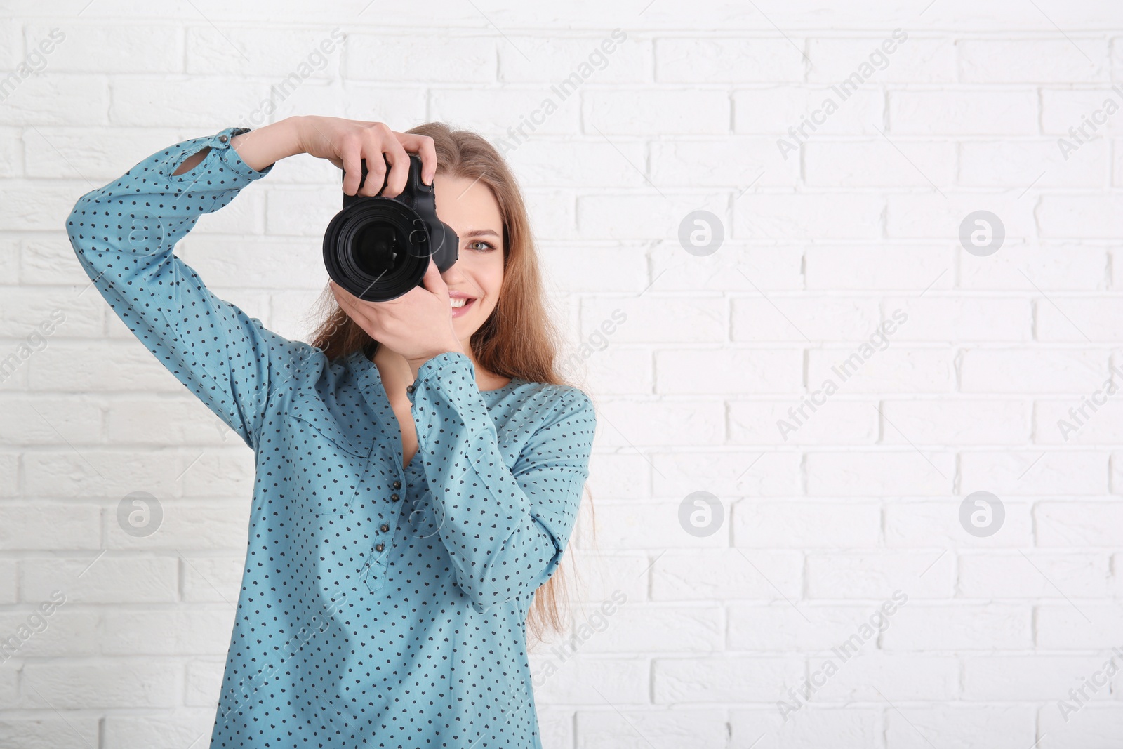Photo of Female photographer with camera on brick background