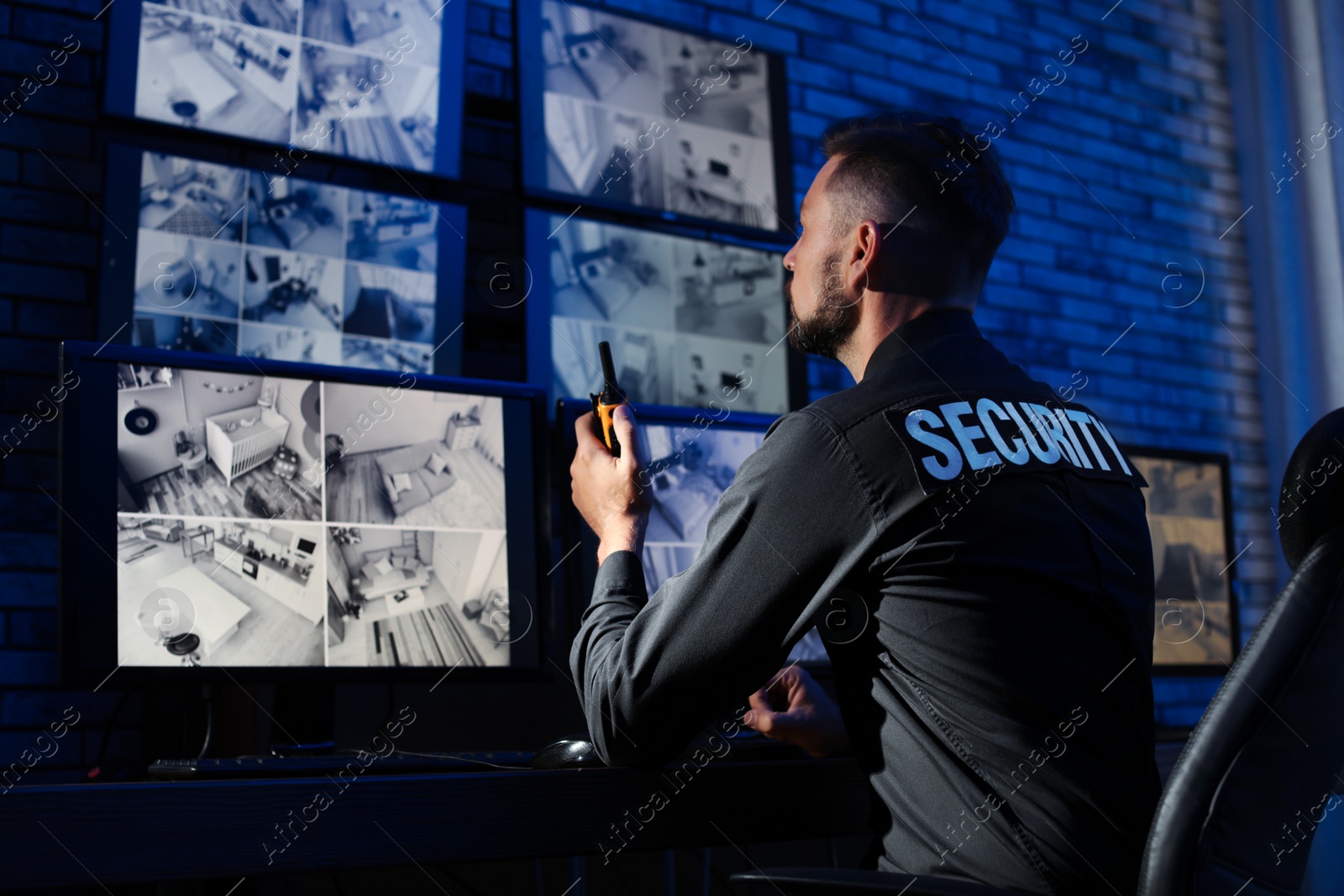 Photo of Male security guard with portable transmitter monitoring modern CCTV cameras indoors