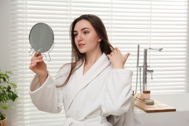 Photo of Beautiful woman looking in mirror in bathroom