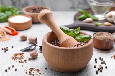 Mortar with pestle and different spices on light grey table