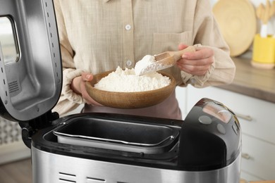 Making dough. Woman adding flour into breadmaker machine, closeup