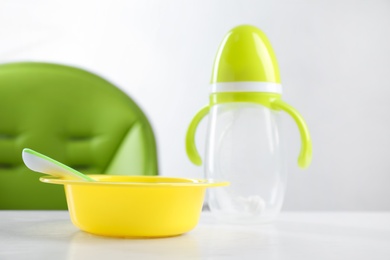 Set of plastic dishware on white wooden table. Serving baby food